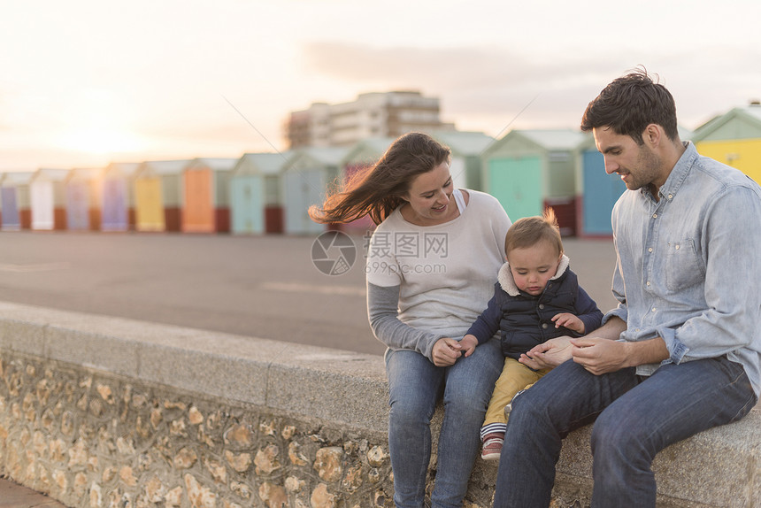 坐在沙滩墙上的年轻家庭图片