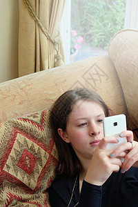 坐在沙发上打智能电话字的年轻妇女头图片