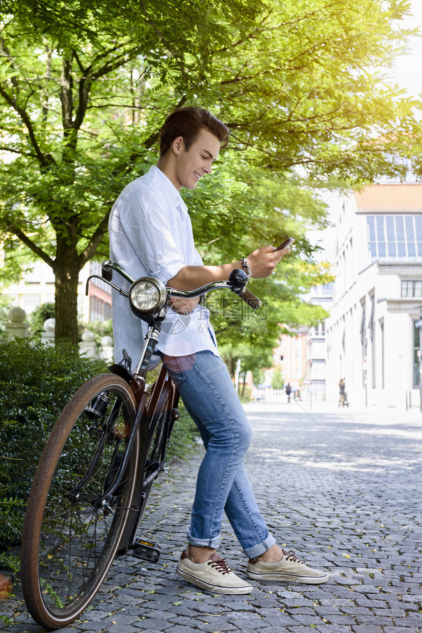年轻人的侧面观仰视自行车智能手机微笑图片