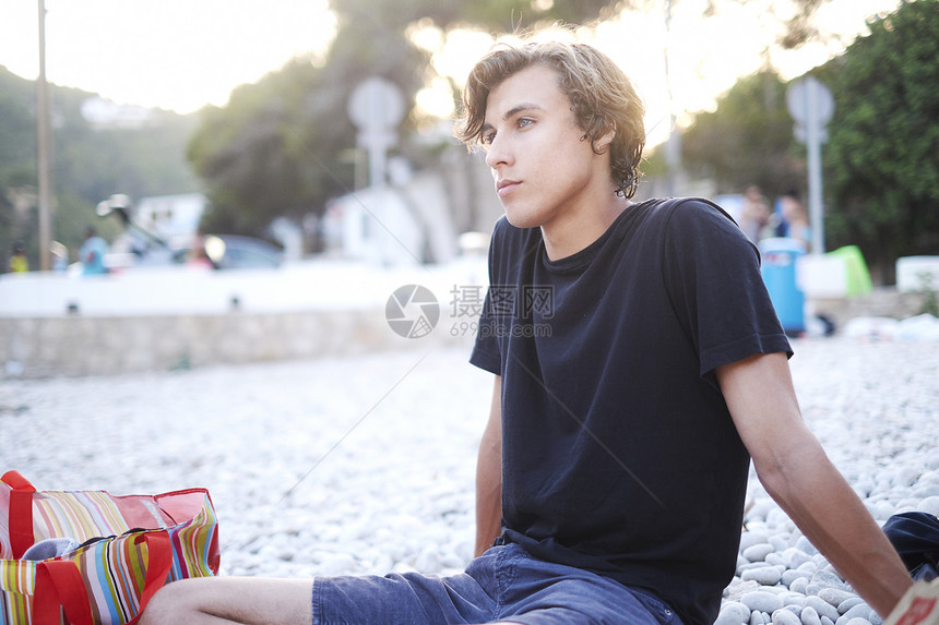 坐在西班牙哈韦亚海滩外看望的年轻人图片