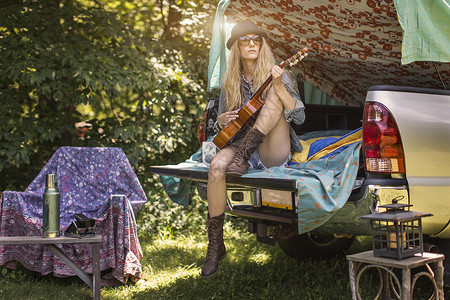 露营时年轻女子在汽车后备箱谈吉他图片