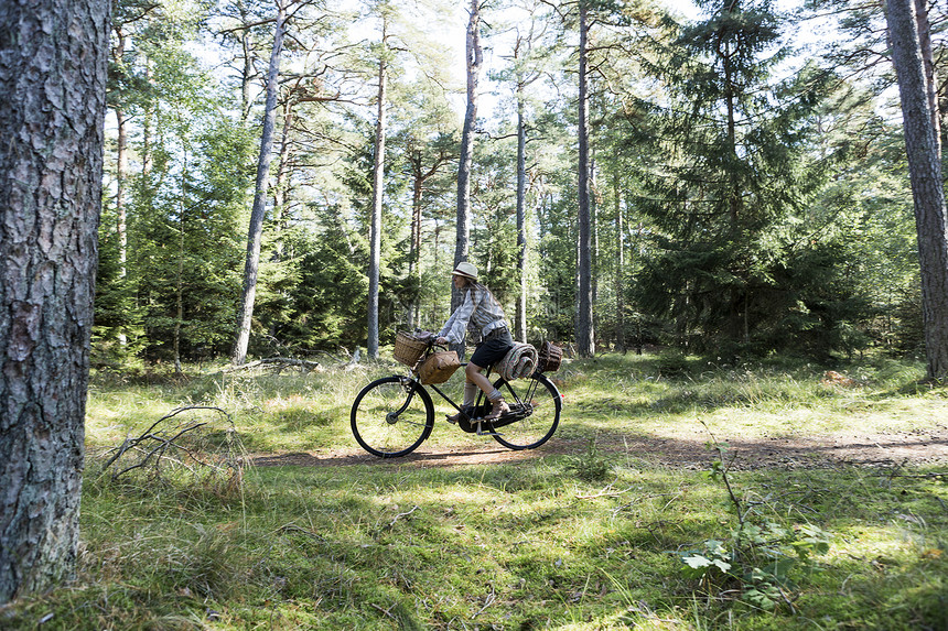 在森林中带着野餐篮子骑自行车的少女图片