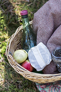 有水瓶跟水果的野餐篮子在草地上图片