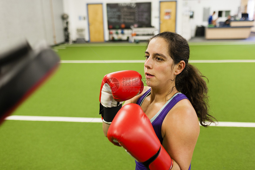 中年成妇女穿着拳击手套在健身房工作图片