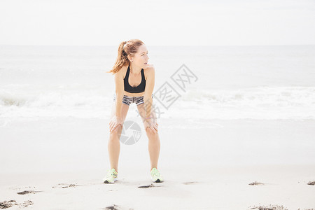 成年妇女站在沙滩上双手握膝休息图片
