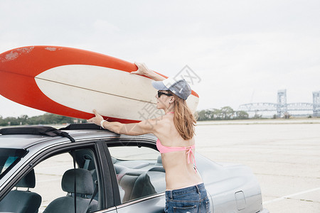 成年女子从车顶取下冲浪板图片