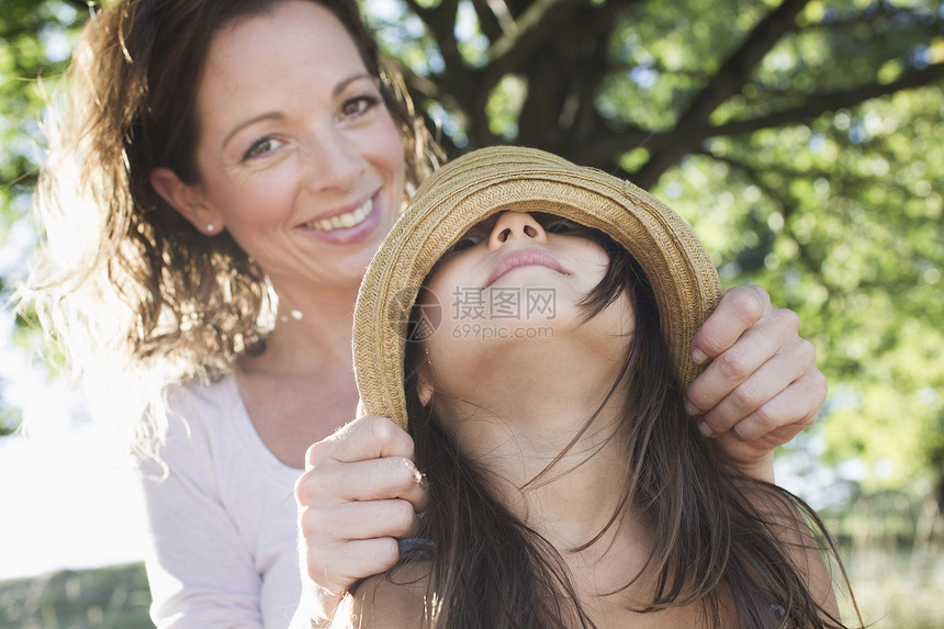 母亲在公园里用草帽遮住女儿的眼睛图片