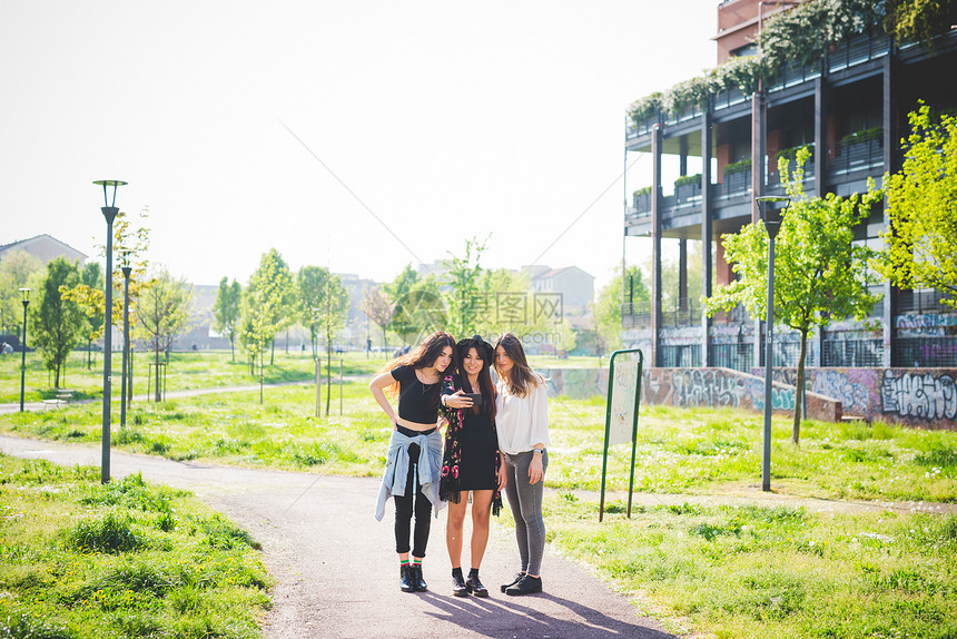 三名年轻女朋友在公园阅读智能手机短信图片