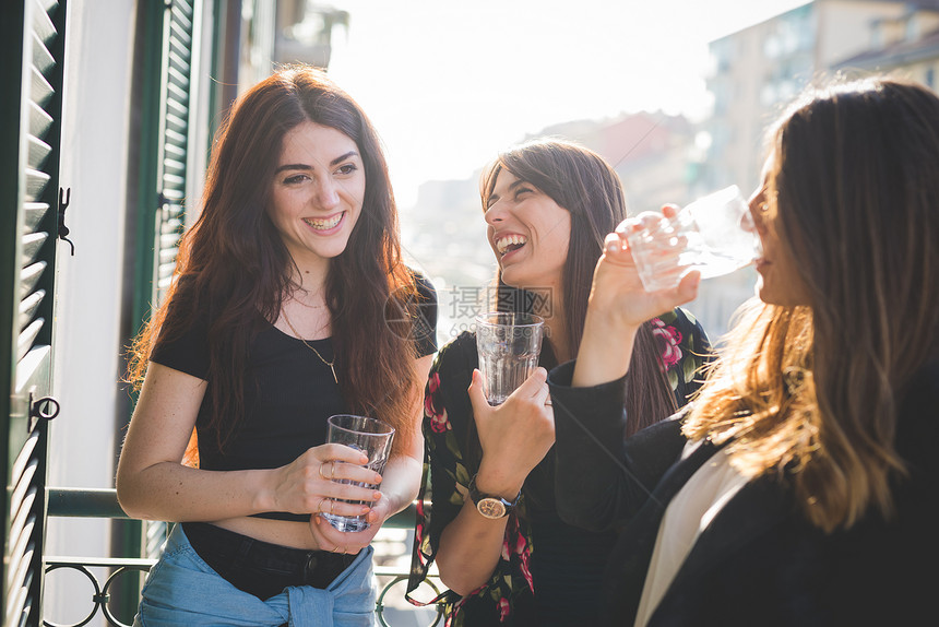 三名年轻女朋友在水边阳台欢笑和聊天图片