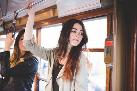 两名年轻妇女乘坐城市电车旅行图片