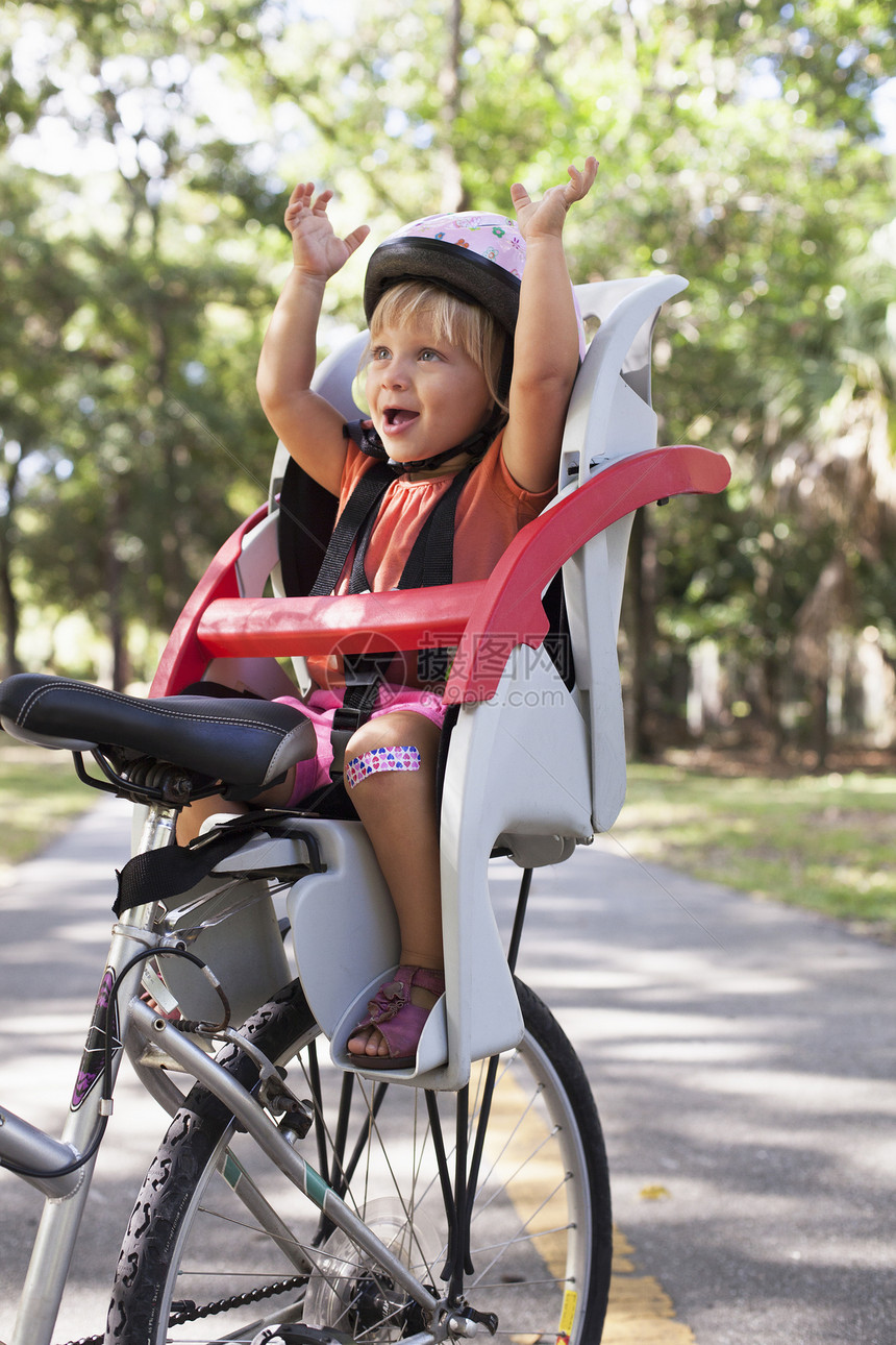 坐在儿童自行车座位上享受旅程的年轻女孩图片