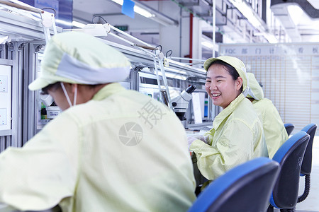 在生产电子路板的工厂质量检查站的年轻女性图片