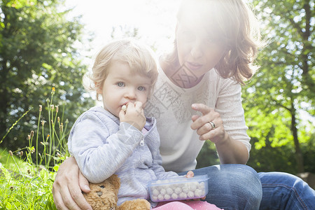 母亲和女幼儿在公园吃甜食图片