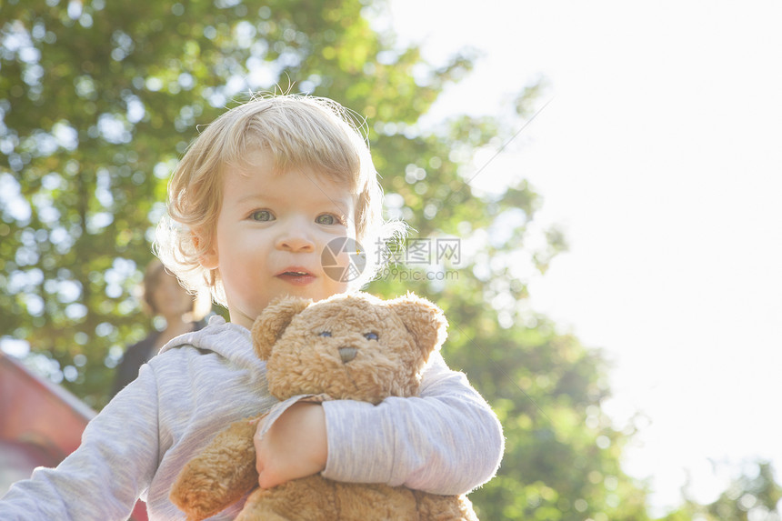 游乐场拥抱泰迪熊的可爱女幼儿图片