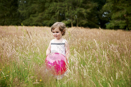 草地上拿着气球的小女孩图片