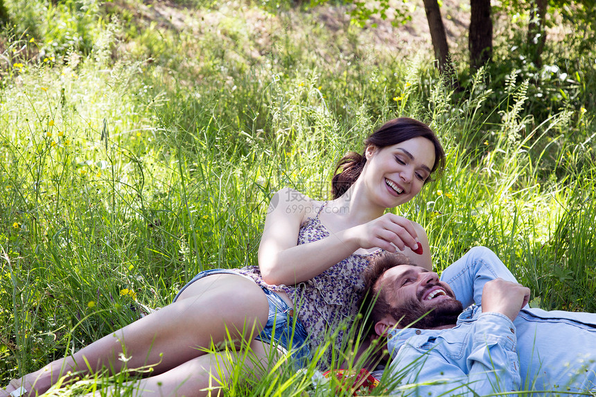 躺在草地上吃草莓的年轻夫妇图片