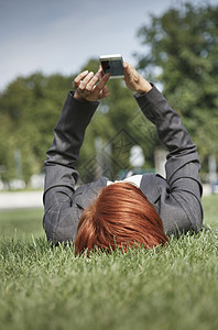 一名女士躺在草地上用智能手机图片