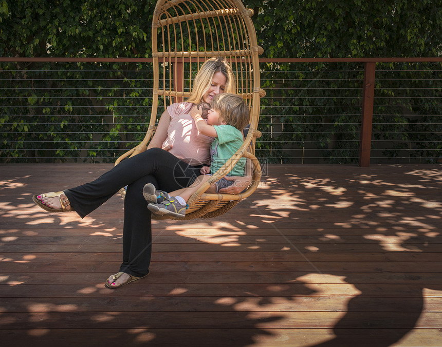 孕妇和儿子在花园摇椅上放松图片