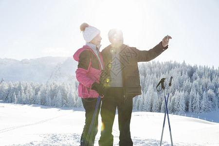 一对老年夫妇在雪地上用智能手机拍照图片