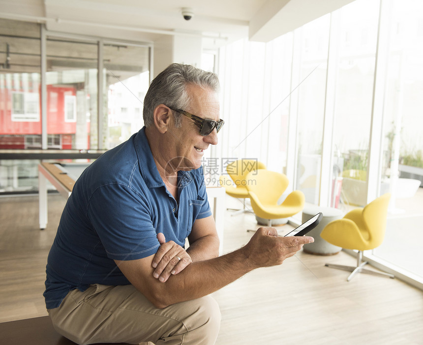 戴着太阳眼镜的男性阅读智能手机短信图片