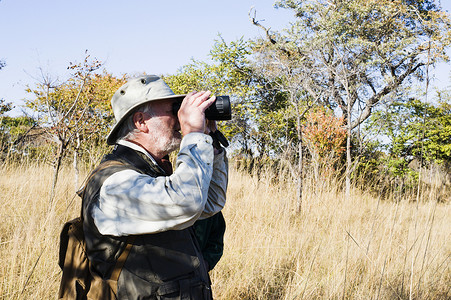 男子在赞比亚公园通过望远镜看远方高清图片