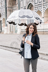 一名年轻女子手持雨伞看着摄像机微笑图片