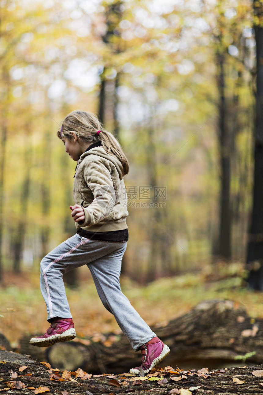 秋林中女孩跳过树干图片