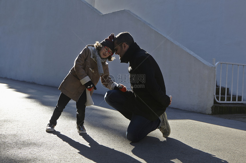 父亲和女儿在街上头戴大衣巾身着图片