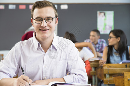 男学生的肖像坐在教室的办公桌前图片