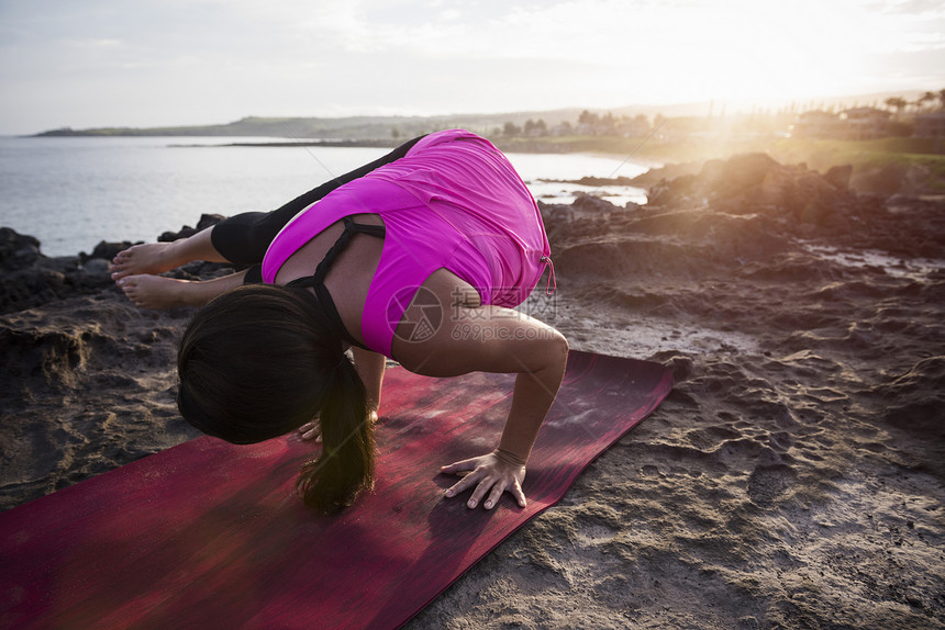 海岸练习平衡瑜伽的年轻女性图片
