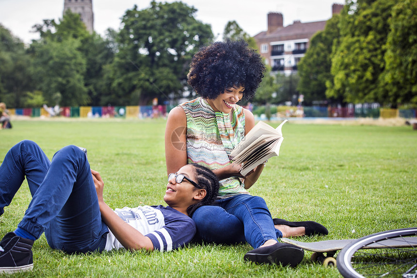 男孩和母亲在公园放松和阅读书图片