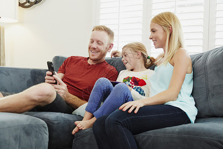 百慕大短裤在客厅沙发上聊天看手机的一家人背景