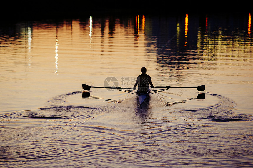 年轻人在日落时河上划船图片