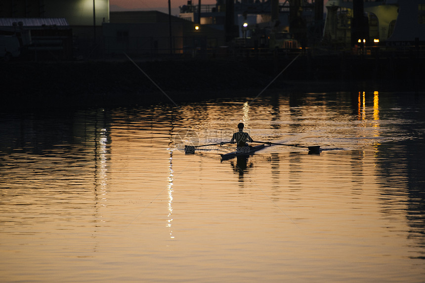 年轻人在日落时河上划船图片
