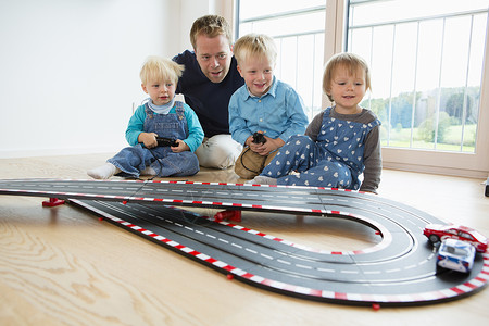 f3赛车在客厅地板上玩具赛车的中年男子和3名中幼儿背景