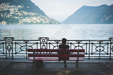 瑞士卢加诺湖公园长椅上女人侧影的后视图图片