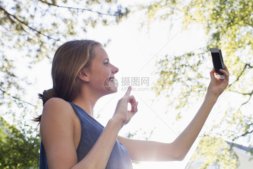 少女在公园装扮智能手机自拍图片