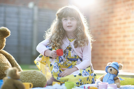 女孩在花园野餐时带着玩具茶杯图片