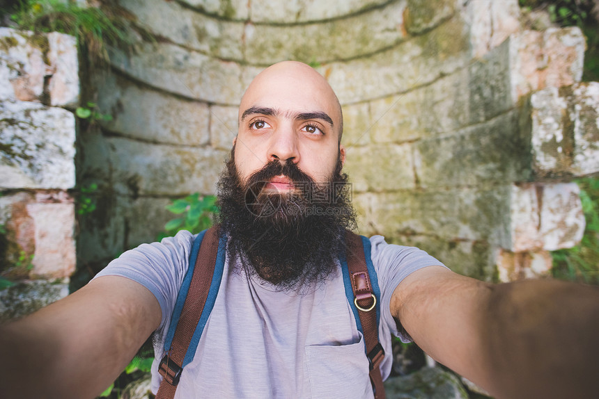 意大利加尔达留胡子的男人对着旧砖墙摆姿势图片
