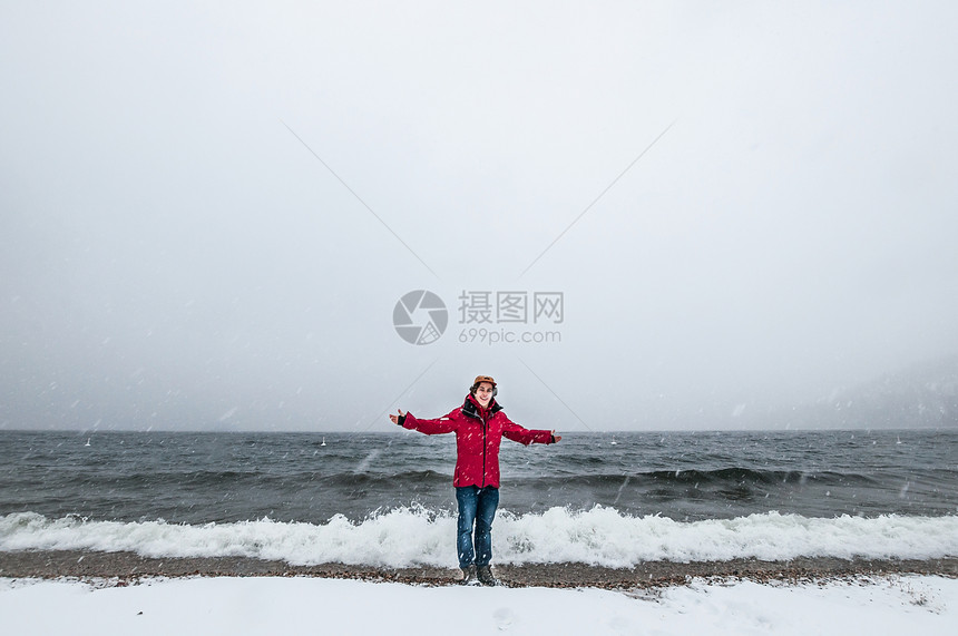 身穿红色大衣在海洋中划桨的青年男子全长前视线图片