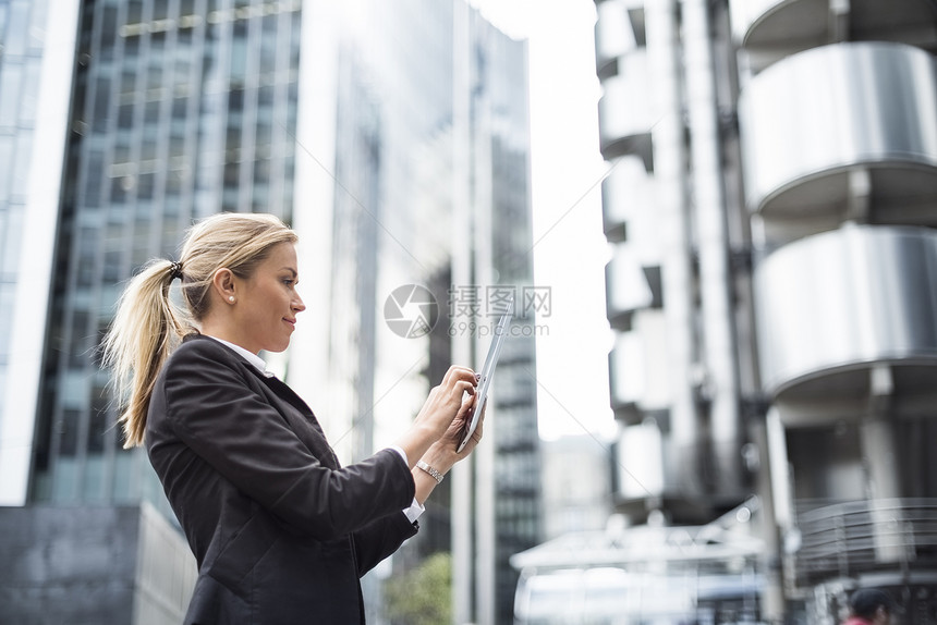 在联合王国伦敦街上使用数字平板牌的女商人图片