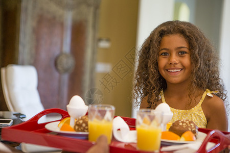 早餐托盘前微笑的年轻女孩图片