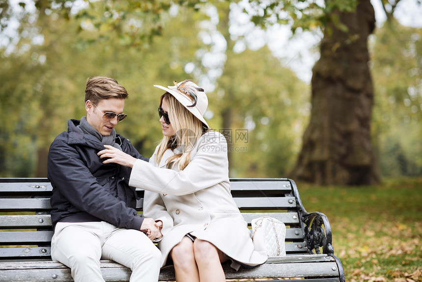 坐在公园长椅上的时尚年轻夫妇图片