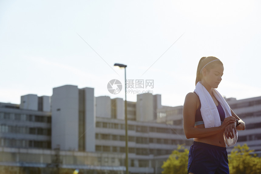 年轻女选手在城市屋顶看运动手表图片