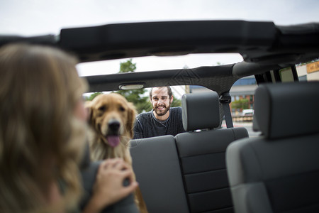 吉普车上的年轻女子看着狗和男朋友图片