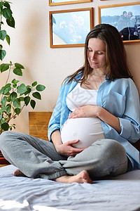 孕妇坐在床上摸着自己的肚子图片