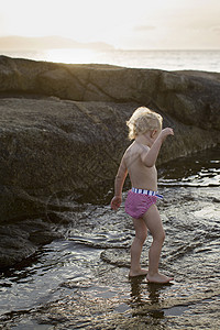 蹒跚学步的女婴在海上玩耍图片