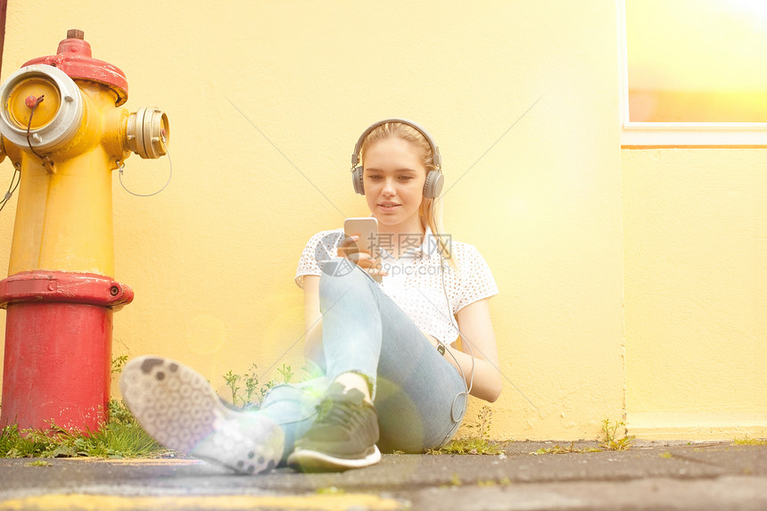 坐在街上手持智能机的青年女孩图片