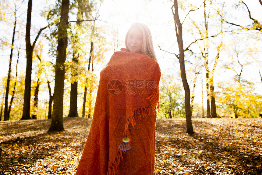 披着毛毯的女性在秋天的树林里图片