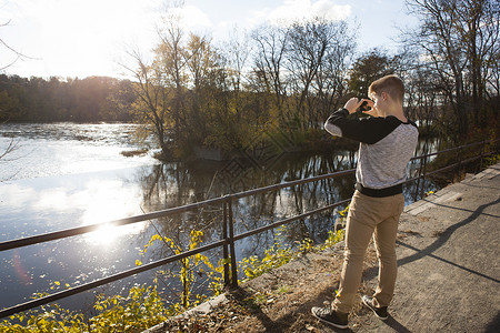 在秋天公园拍摄日光河的青少年图片